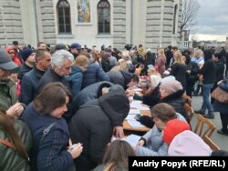 Хмельницкий шіркеуінің алдында петицияға қол қойып жатқан адамдар.