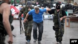 Донецк қаласындағы облыстық әкімдікті басып алған «Восток» батальонының жауынгерлері ресейшіл белсендіні ұстап әкетіп барады. 29 мамыр 2014 жыл. 