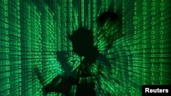 An illustration picture shows a projection of binary code on a man holding a laptop computer - generic