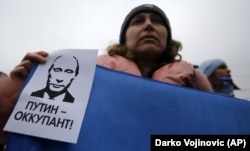 Женщина держит плакат с надписью «Путин - оккупант» во время митинга против российской аннексии Крыма. Симферополь, 11 марта 2014 года