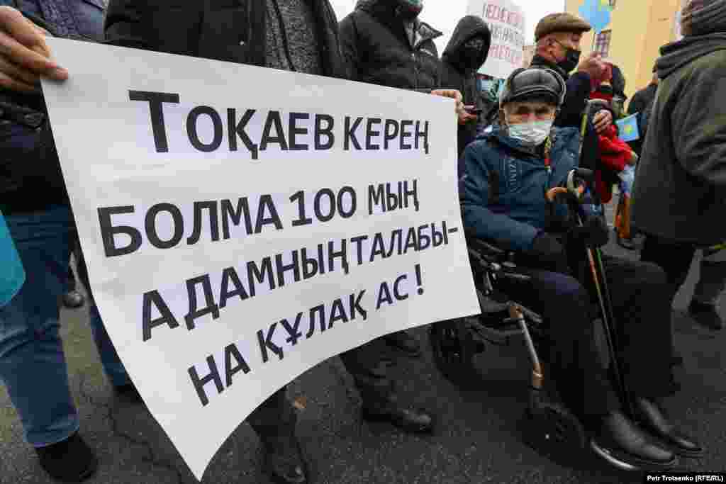 Мүгедек арбасына отырған ер кісі Алматыдағы митингіде. Плакатта &quot;Тоқаев керең болма, 100 мың адамның талабына құлақ ас!&quot; делінген. Тамыз айында Демократиялық партияны құру жөніндегі Жанболат Мамай бастаған бастамашыл топ Қазақстан президенті Қасым-Жомарт Тоқаевтың әкімшілігіне несие амнистиясын жариялау туралы 100 мыңға тарта өтініш тапсырылғанын айтты.